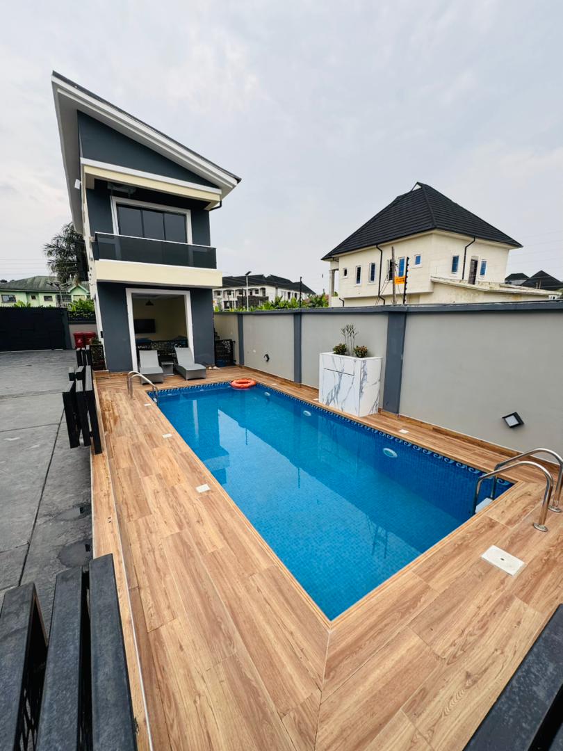 The swimming pool and its wooden deck beside the building