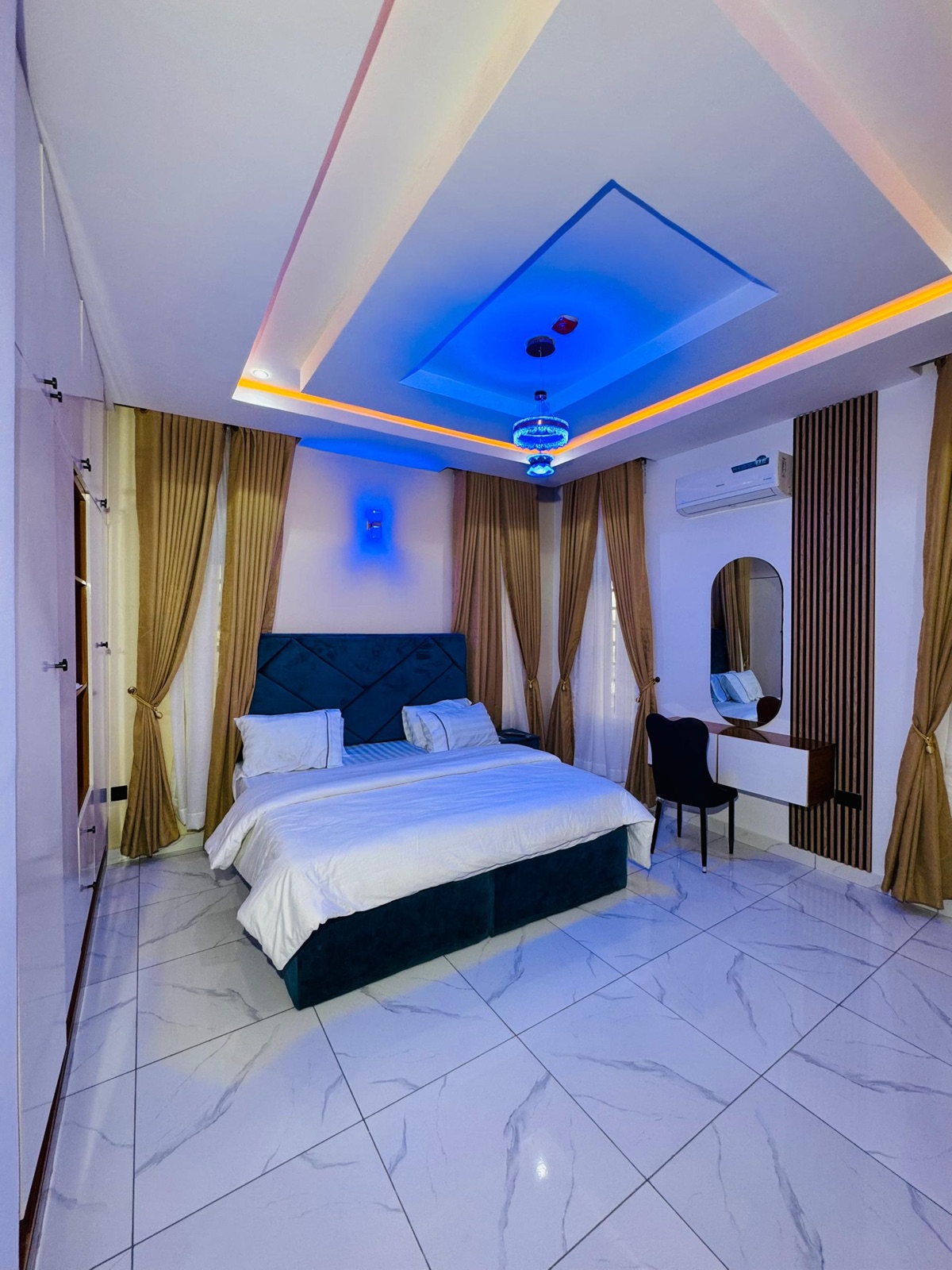 A bedroom with a navy headboard and a dressing mirror